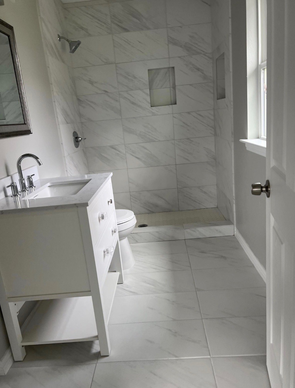 Marble shower and white vanity after a bathroom clean